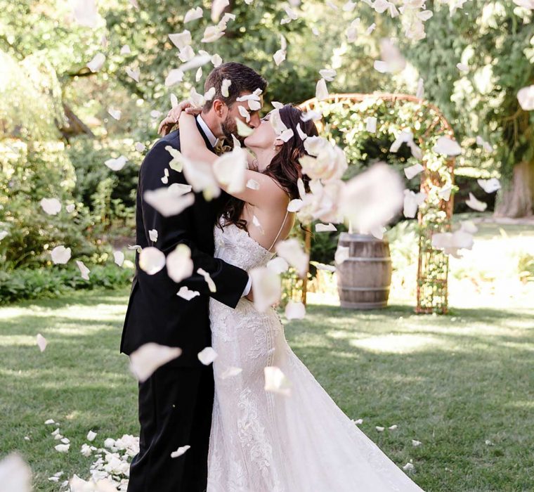 Wedding couple kissing with rose petals falling