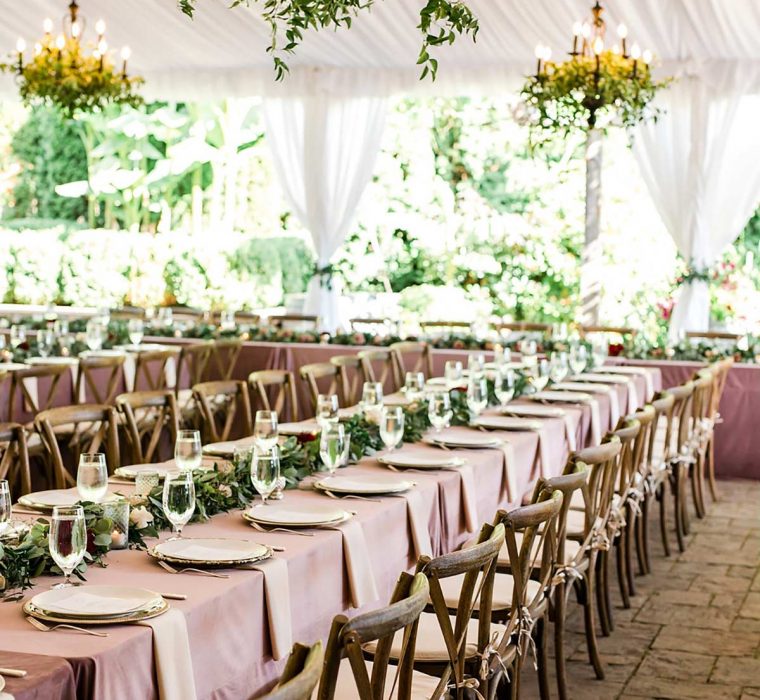 Elegant wedding tent table set up with rose table cloths and wood chairs