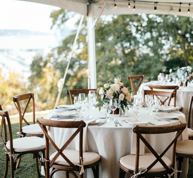 Outdoor wedding table setting under tent with wood chairs
